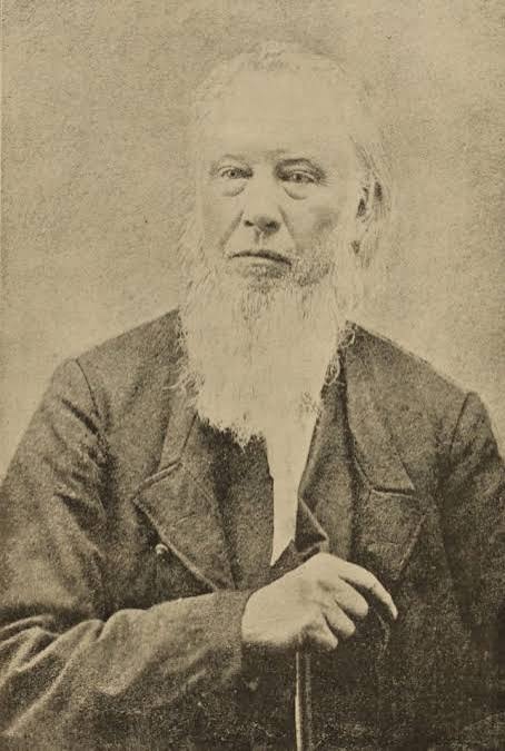 Nineteenth-century portrait photograph of an aged, white-bearded minister — period reference for the invented character.