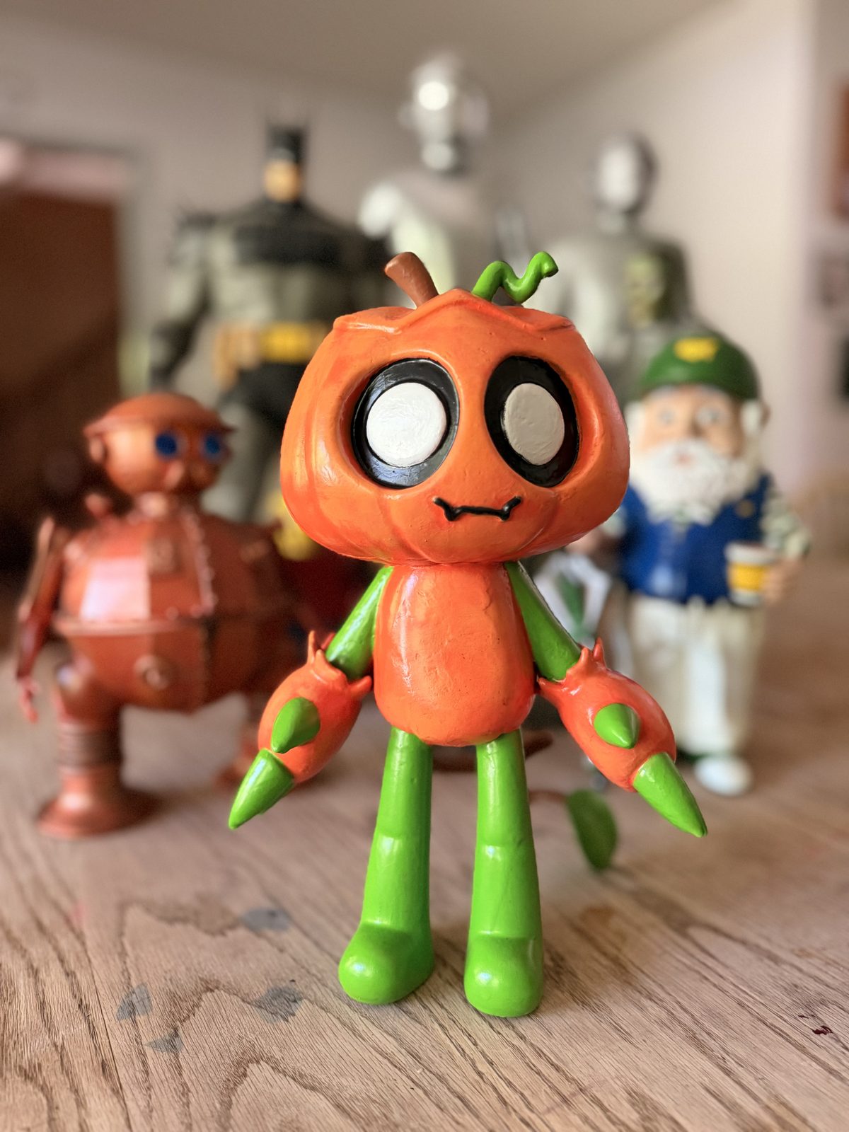 Pumpkin-headed character with green legs and big white eyes, hand-painted.