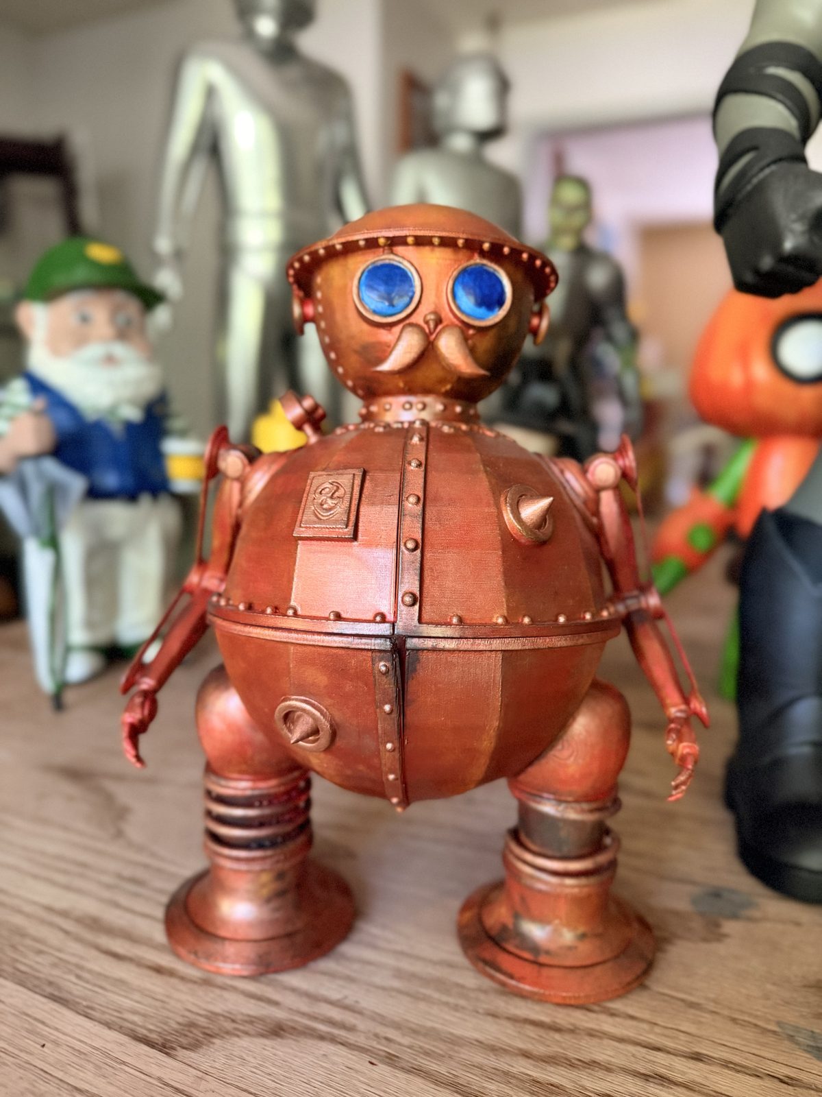 Copper steampunk robot figure with blue eyes and a riveted body, hand-painted.