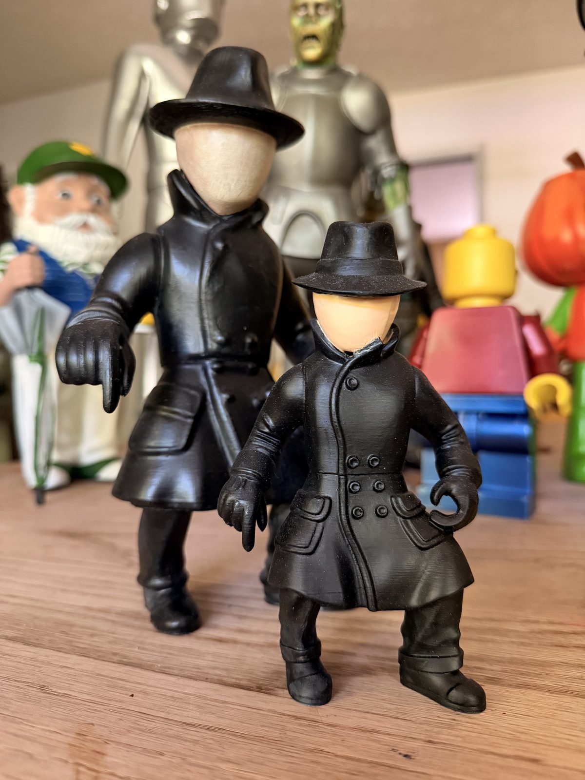 Two Dick Tracy 'The Blank' figures, faceless characters in black trench coats and fedoras.